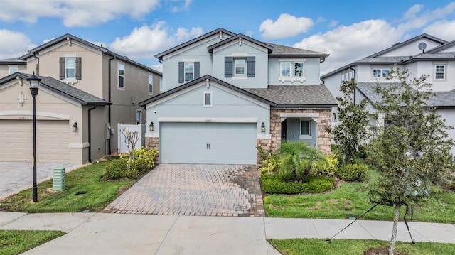 traditional-style home featuring stone siding, decorative driveway, an attached garage, and stucco siding