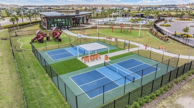 view of tennis court with a residential view, fence, and playground community