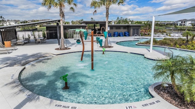 view of swimming pool featuring a patio area, a water play area, and fence