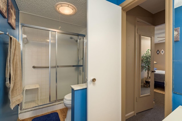 ensuite bathroom featuring toilet, ensuite bath, a shower stall, and a textured ceiling