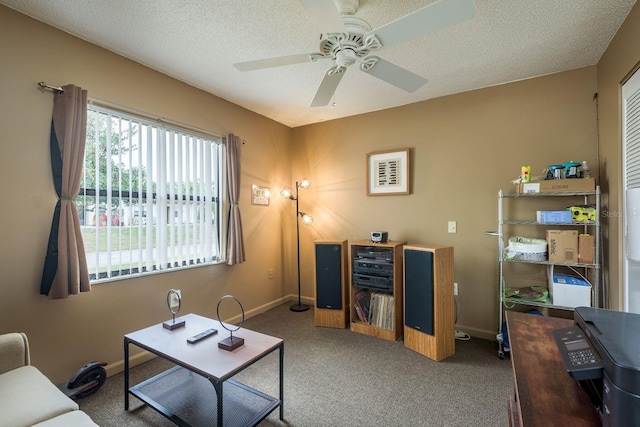 living area featuring a textured ceiling, dark carpet, a ceiling fan, and baseboards