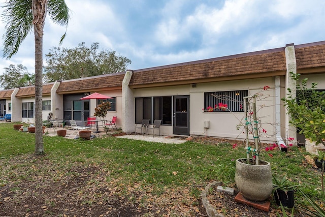 back of house with a patio area, a yard, and stucco siding