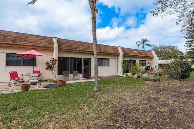 back of property featuring mansard roof, a patio, and a yard