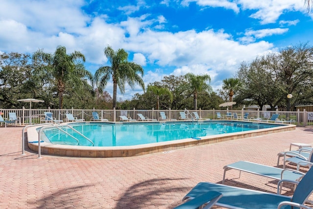 community pool with a patio area and fence