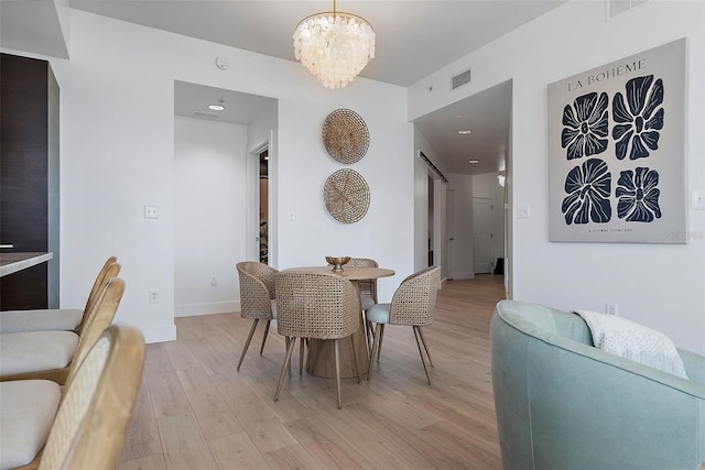 dining area with light wood-style floors, a chandelier, visible vents, and baseboards