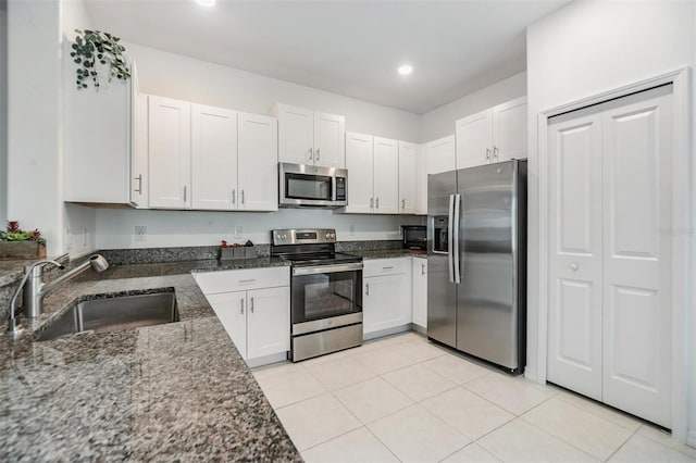 kitchen with dark stone countertops, white cabinetry, appliances with stainless steel finishes, and a sink