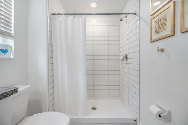 full bath featuring a stall shower and toilet