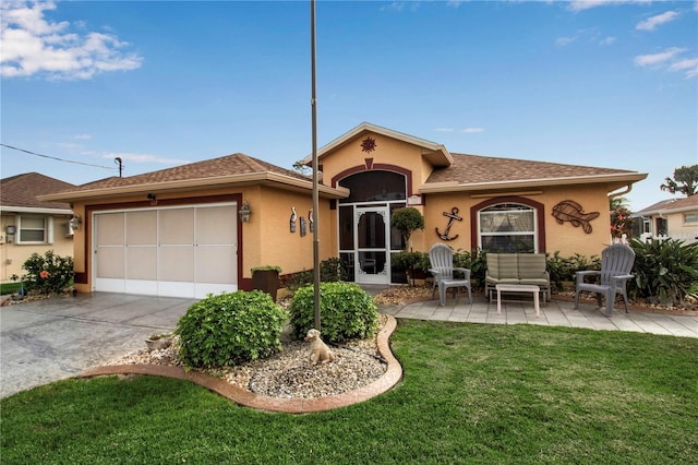 view of front of house with stucco siding, concrete driveway, an attached garage, a front yard, and a patio area