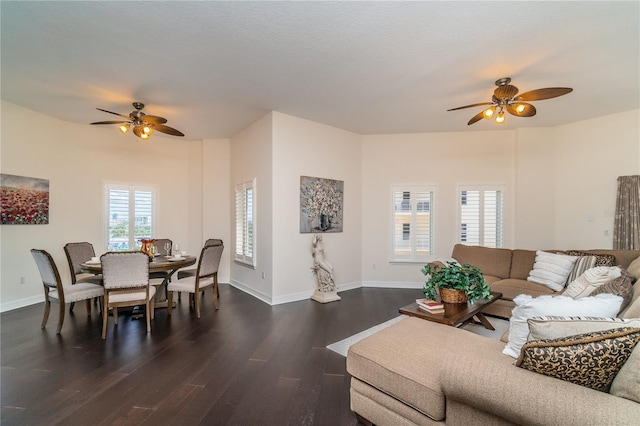 living room with ceiling fan, baseboards, and dark wood-type flooring