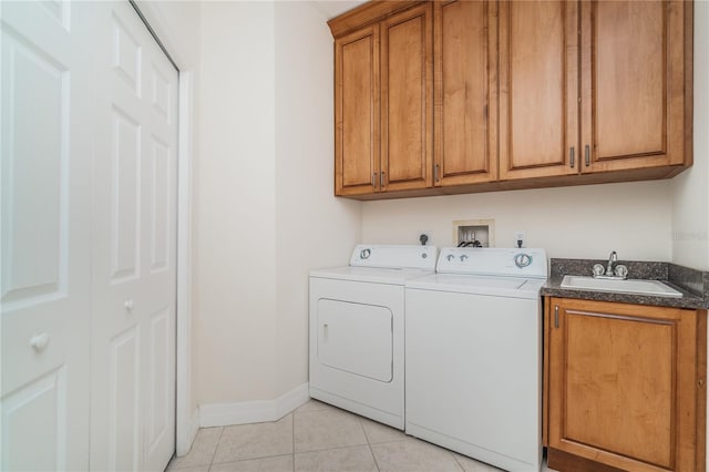 laundry area featuring cabinet space, light tile patterned floors, baseboards, separate washer and dryer, and a sink