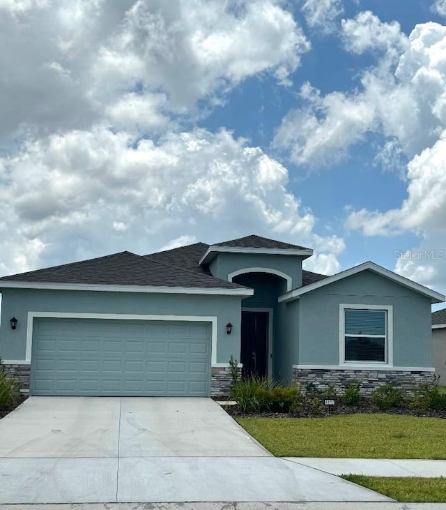 ranch-style house featuring stone siding, driveway, an attached garage, and stucco siding