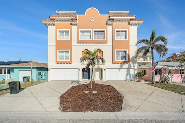 view of front facade with driveway, a tile roof, a garage, and stucco siding