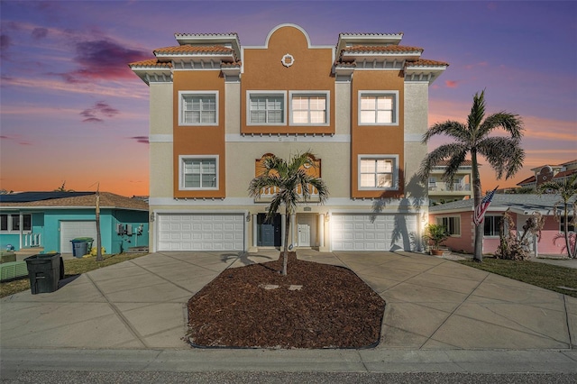 view of front of home with a garage, concrete driveway, and stucco siding