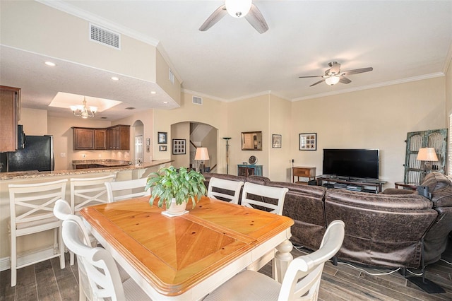 dining area with ceiling fan with notable chandelier, arched walkways, visible vents, and wood finish floors