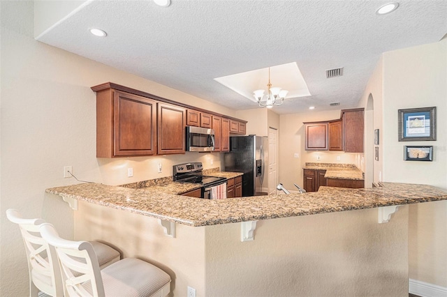 kitchen with appliances with stainless steel finishes, a breakfast bar, visible vents, and a peninsula