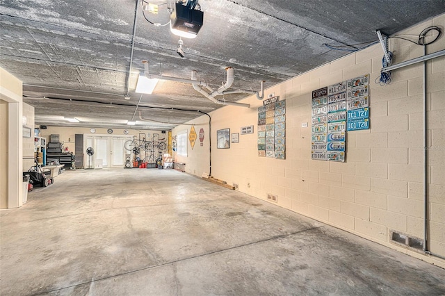 garage with a garage door opener and concrete block wall