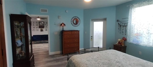 bedroom with wood finished floors, visible vents, and baseboards