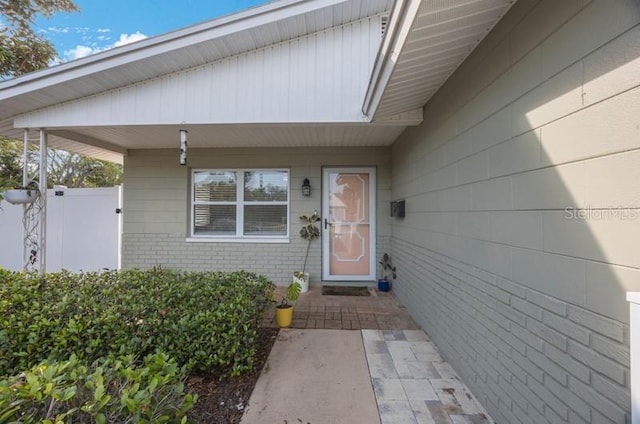 property entrance featuring fence and brick siding