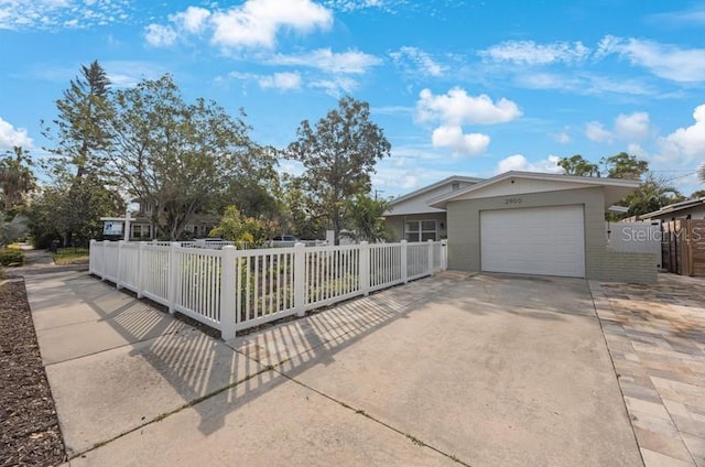 view of front of home with a fenced front yard, driveway, and a garage