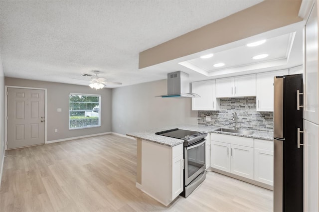 kitchen featuring appliances with stainless steel finishes, white cabinets, a sink, and wall chimney exhaust hood