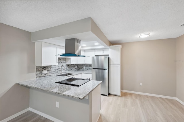 kitchen featuring freestanding refrigerator, white cabinetry, island exhaust hood, and a peninsula