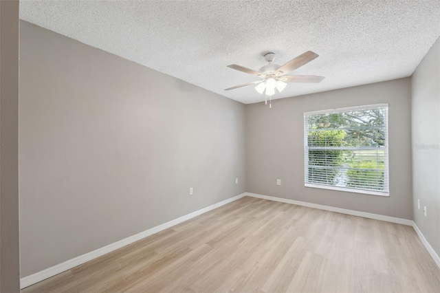 unfurnished room featuring ceiling fan, light wood-style flooring, baseboards, and a textured ceiling