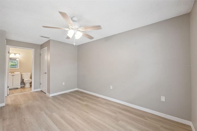 unfurnished bedroom with visible vents, baseboards, connected bathroom, light wood-style flooring, and a textured ceiling