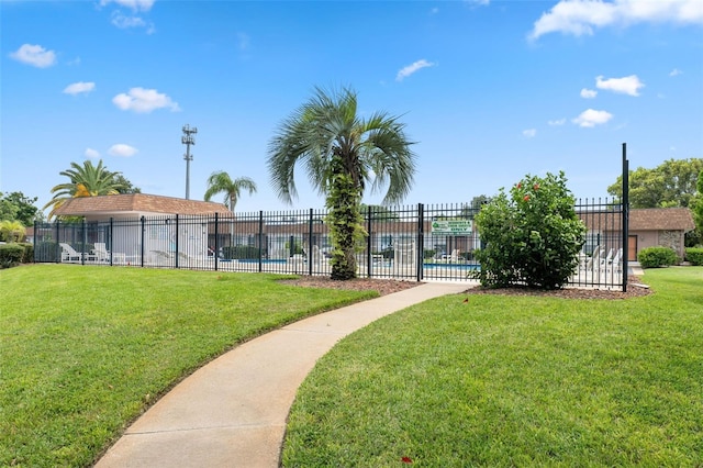 view of home's community with a yard, a swimming pool, and fence