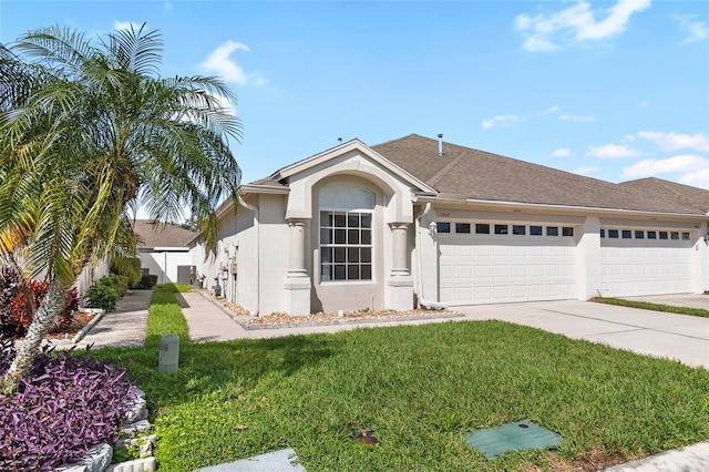 single story home with a garage, a front yard, concrete driveway, and stucco siding