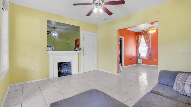 unfurnished living room with baseboards, a ceiling fan, and a fireplace