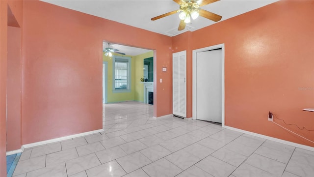spare room with baseboards, ceiling fan, and light tile patterned flooring