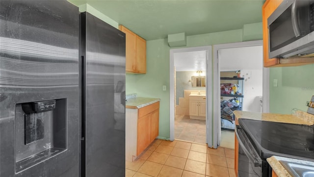 kitchen with light countertops, light tile patterned floors, light brown cabinetry, and stainless steel appliances