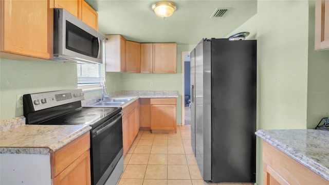 kitchen featuring visible vents, a sink, light countertops, light brown cabinets, and stainless steel appliances