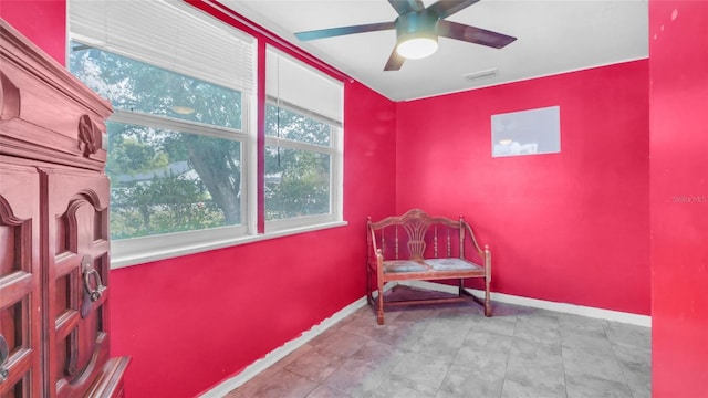 living area featuring baseboards, a ceiling fan, and visible vents