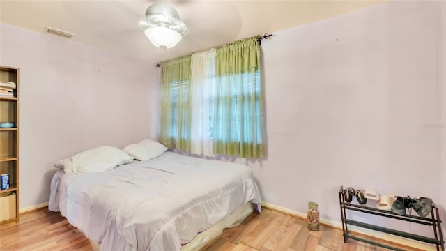 bedroom with baseboards, wood finished floors, and visible vents