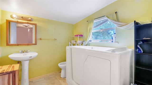 bathroom with toilet, washer / dryer, and a sink