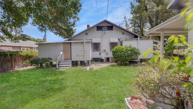 rear view of house with a lawn, fence, a chimney, and entry steps