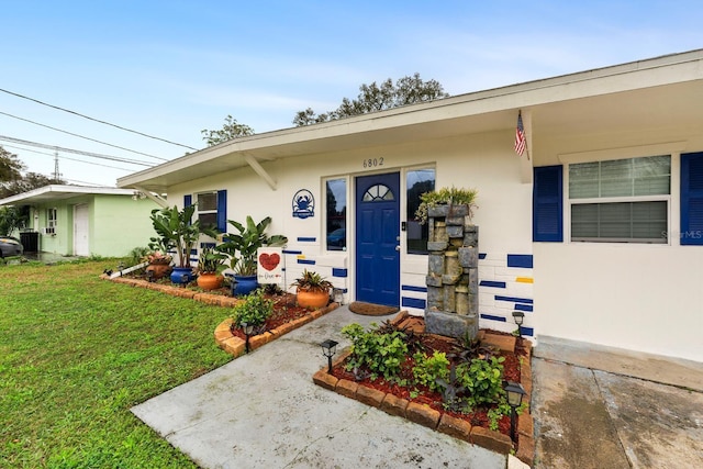 entrance to property featuring a lawn and stucco siding