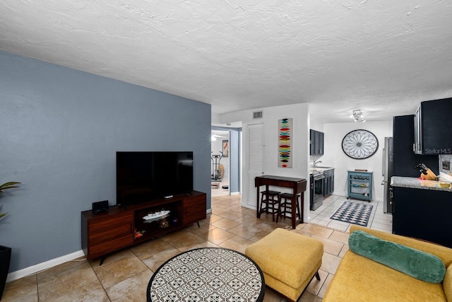 living room with beverage cooler, a textured ceiling, visible vents, and baseboards