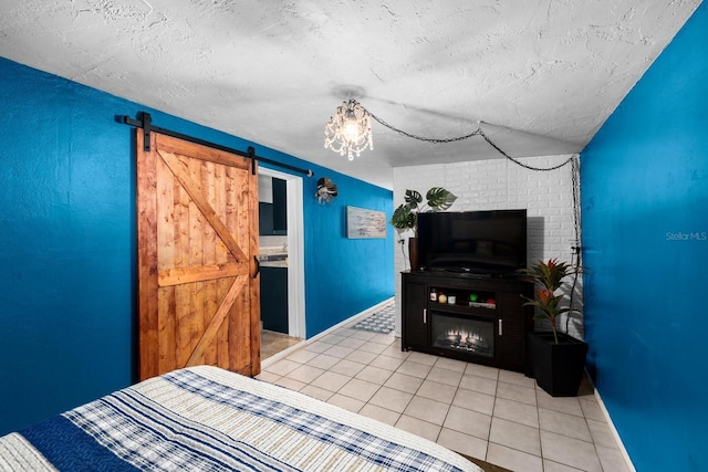 bedroom featuring a textured ceiling, a barn door, light tile patterned flooring, baseboards, and a lit fireplace