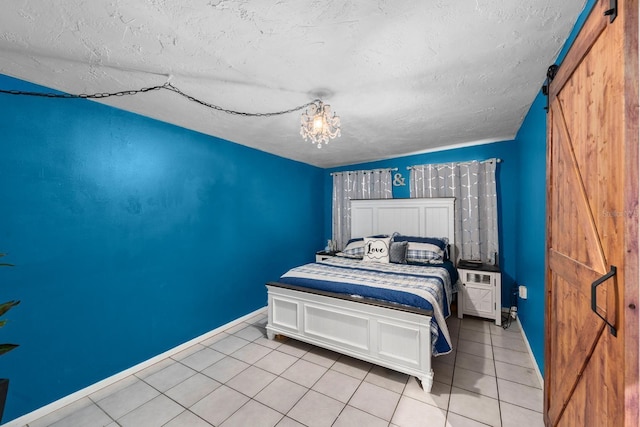 bedroom featuring light tile patterned floors, a barn door, baseboards, and a textured ceiling