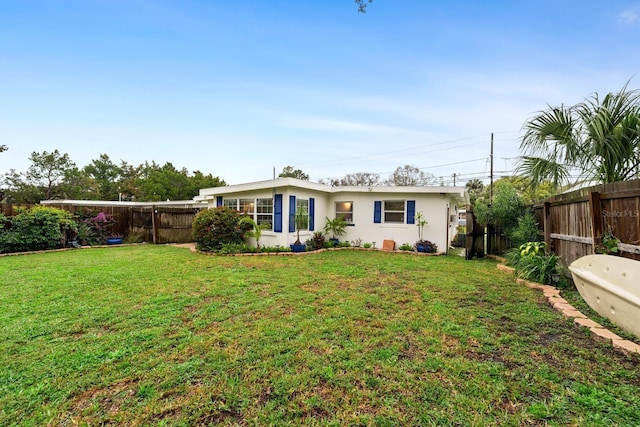 back of house with a lawn, a fenced backyard, and stucco siding