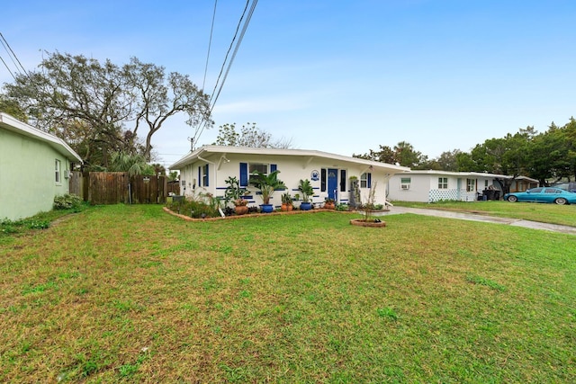 ranch-style house with a front lawn, fence, and stucco siding