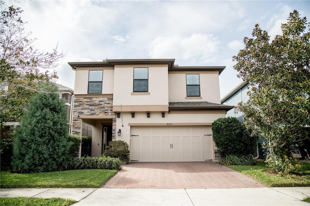 view of front of property with a garage, stone siding, decorative driveway, and stucco siding