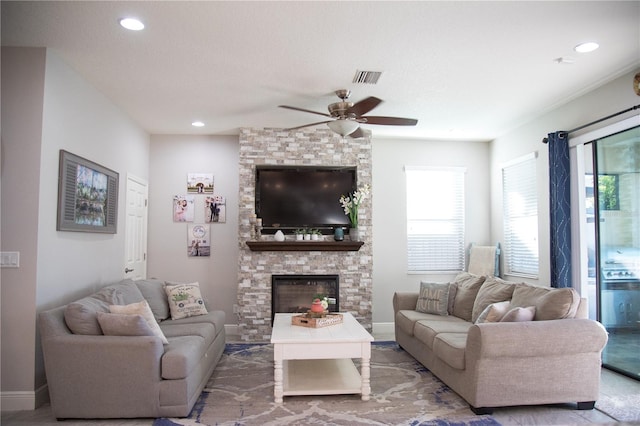 living room featuring baseboards, a fireplace, visible vents, and a ceiling fan