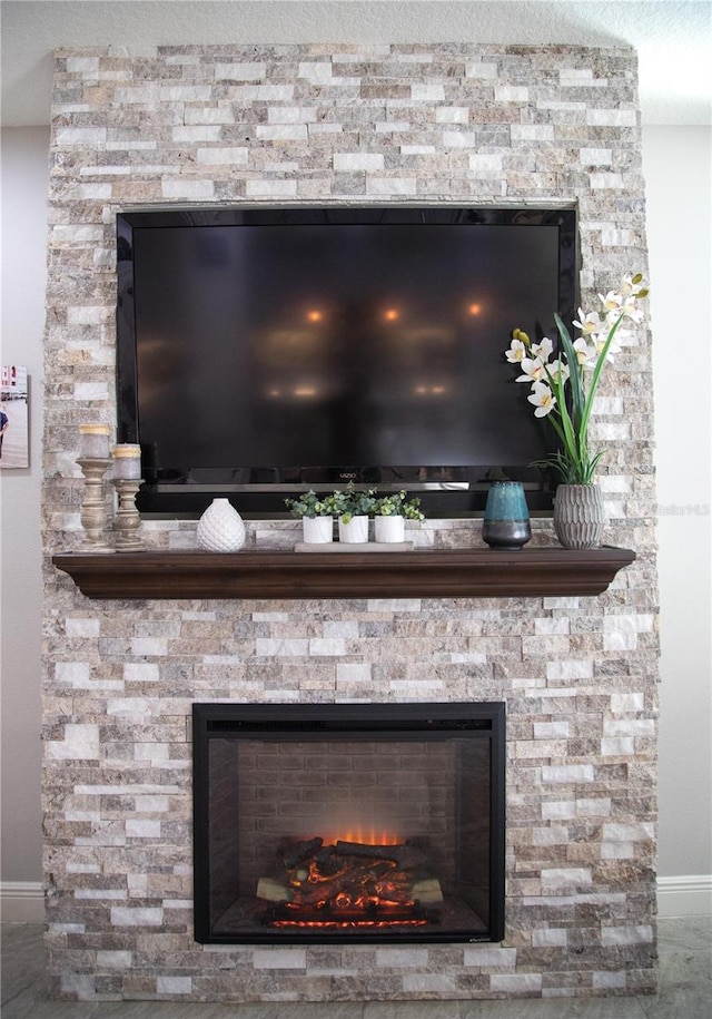 interior details with baseboards, a textured ceiling, and a stone fireplace