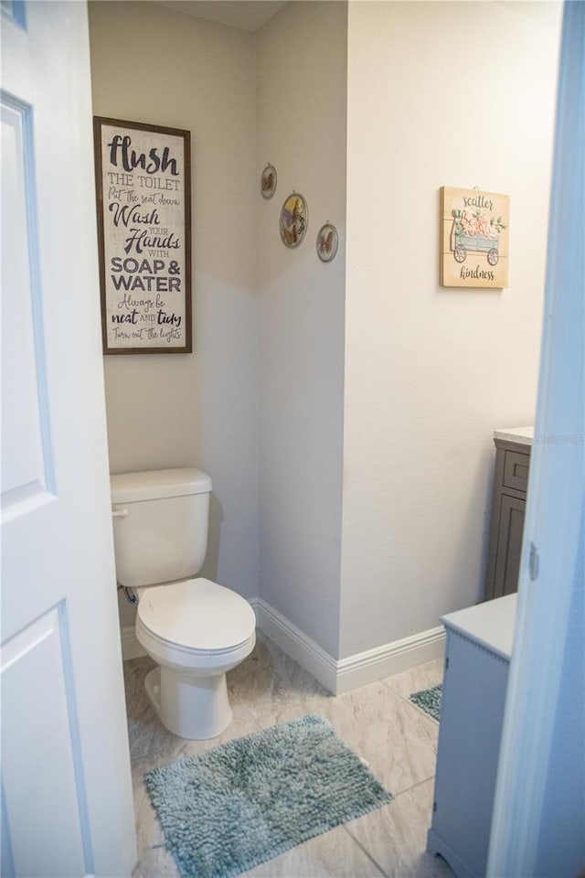 bathroom featuring toilet, vanity, and baseboards