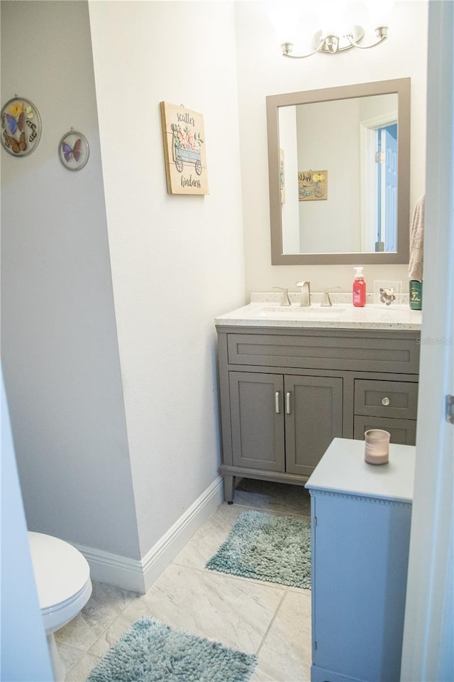 bathroom featuring baseboards, vanity, and toilet