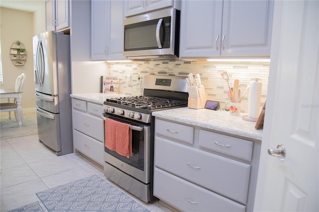 kitchen with light tile patterned floors, tasteful backsplash, appliances with stainless steel finishes, and light stone counters