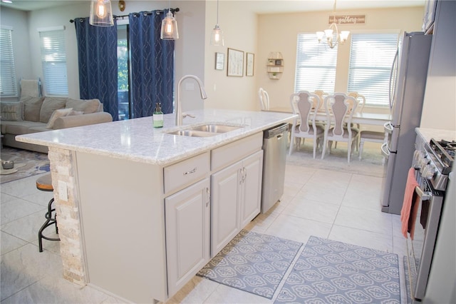 kitchen featuring appliances with stainless steel finishes, open floor plan, a kitchen island with sink, pendant lighting, and a sink